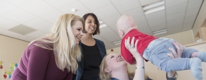 Foto van drie vrouwen (medewerkers) met een baby